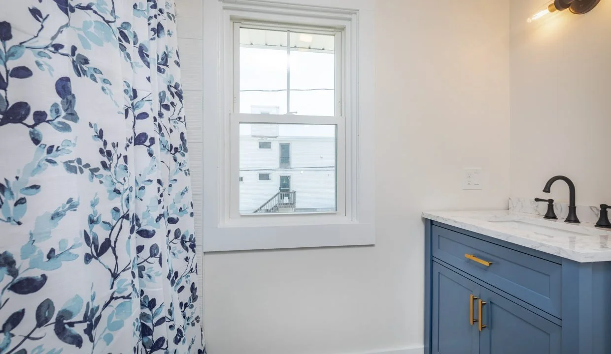 a bathroom with blue cabinets and a blue shower curtain.