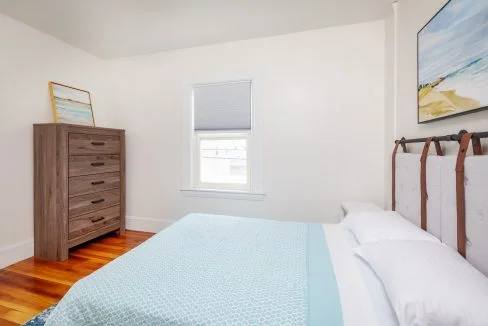 a bedroom with hardwood floors and a blue comforter.