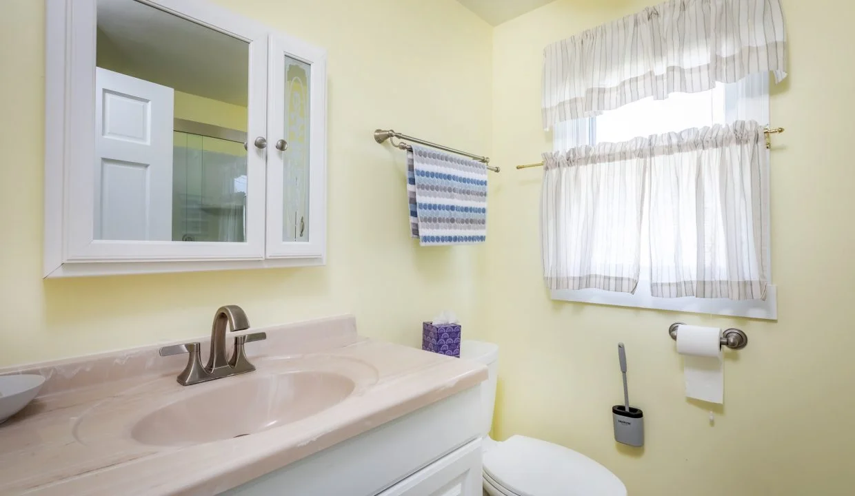 a bathroom with a sink, toilet, and window.