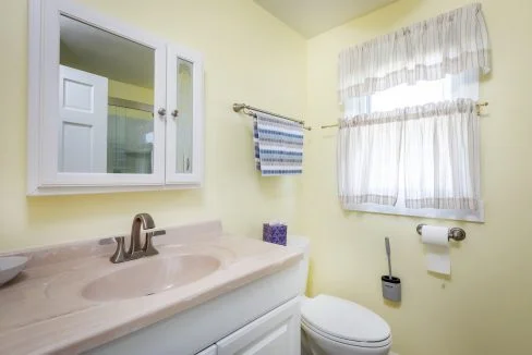 a bathroom with a sink, toilet, and window.