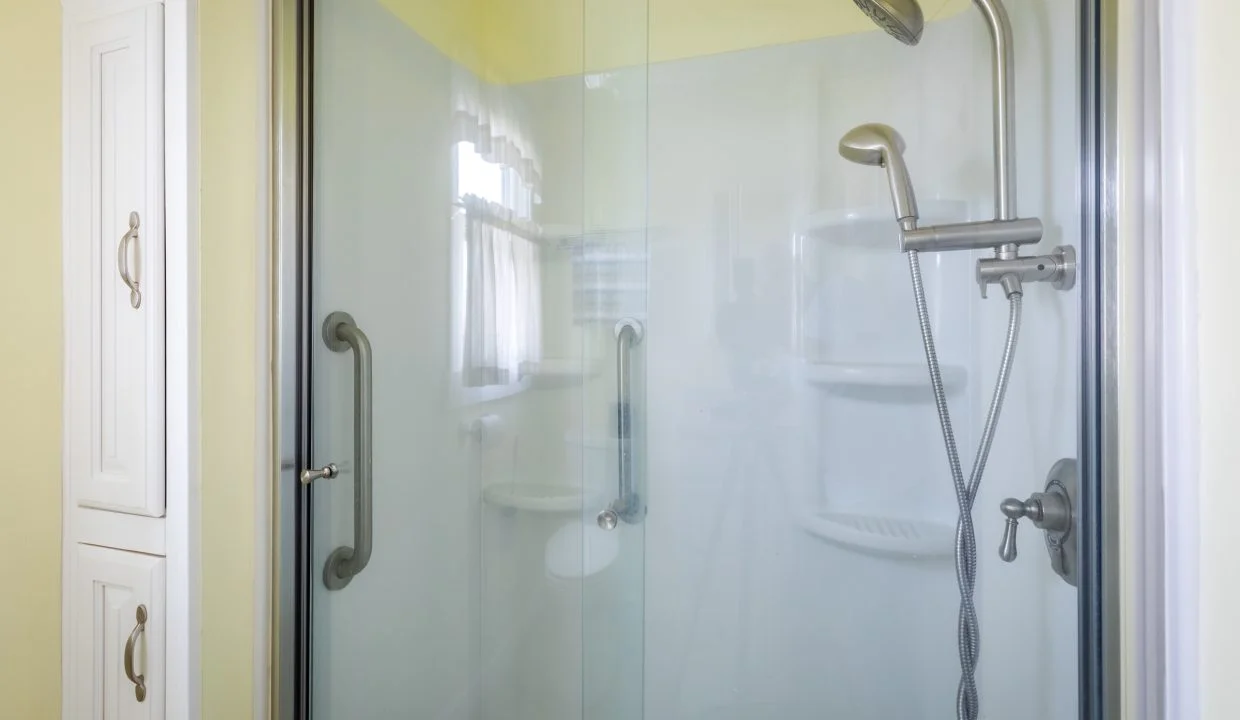 a shower with a glass door and a shower head.