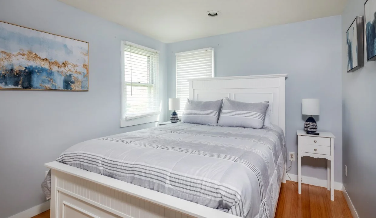 a bedroom with a white bed and a painting on the wall.