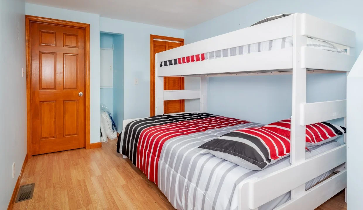 a white bunk bed sitting in a bedroom next to a wooden door.