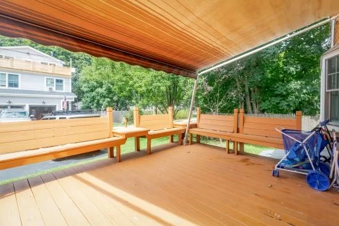 A wooden deck with a bench and chairs.