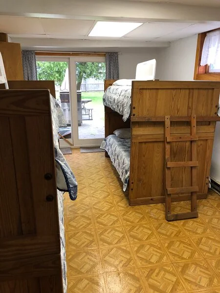A furnished basement room with bunk beds and an open door leading to the backyard.