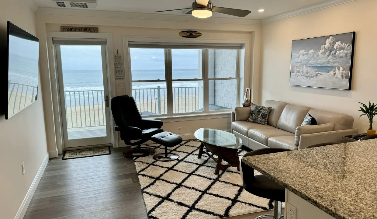 A modern living room with a leather sofa and chair overlooking an ocean view through balcony doors.