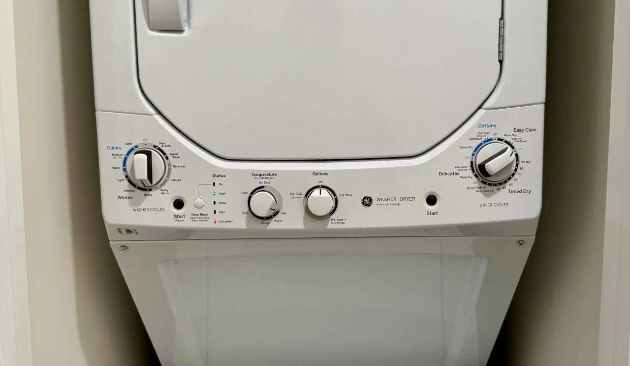 Stacked white washing machine and dryer in a laundry room.