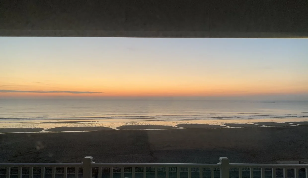 Sunset view over a beach from a balcony.