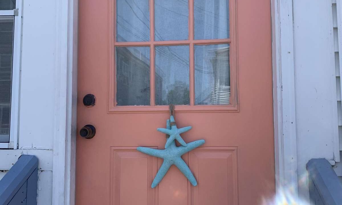 A peach-colored door with a nine-pane window and a blue starfish decoration hanging from it.