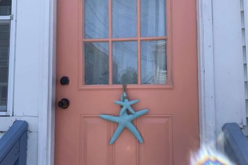 A peach-colored door with a nine-pane window and a blue starfish decoration hanging from it.