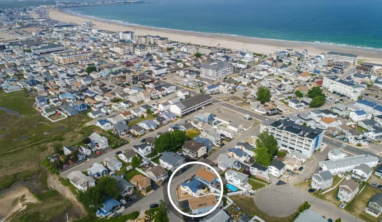 Aerial view of a coastal town with beaches and residential areas. A house near the center is circled in white.